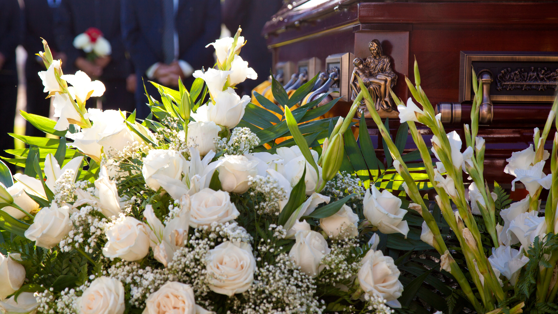 A coffin is surrounded by white flowers at a funeral.