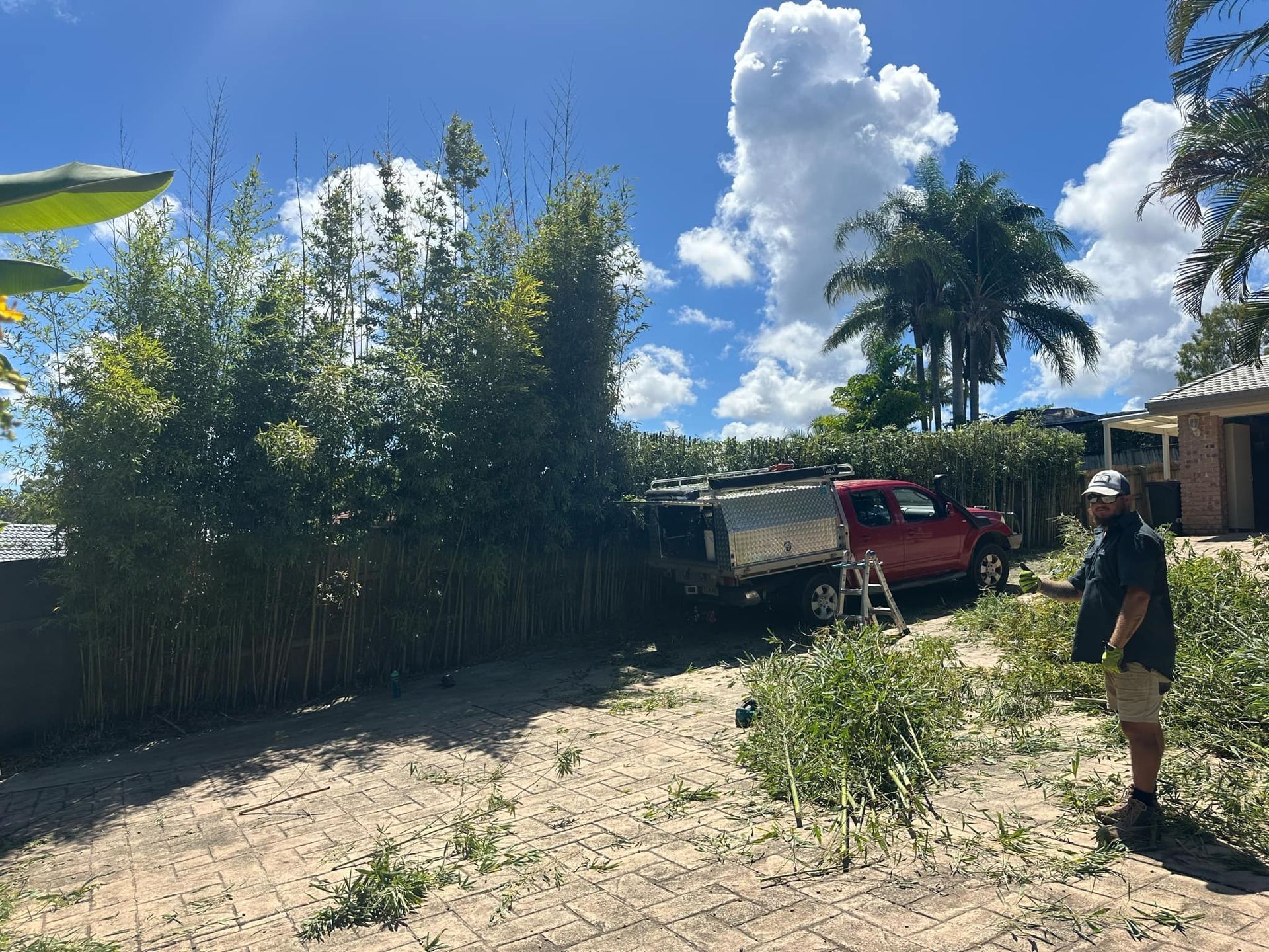 A man is standing in a dirt field next to a red truck | MowAbility Garden Services Gold Coast