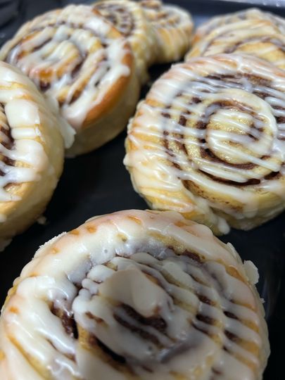 A bunch of cinnamon rolls with icing on them