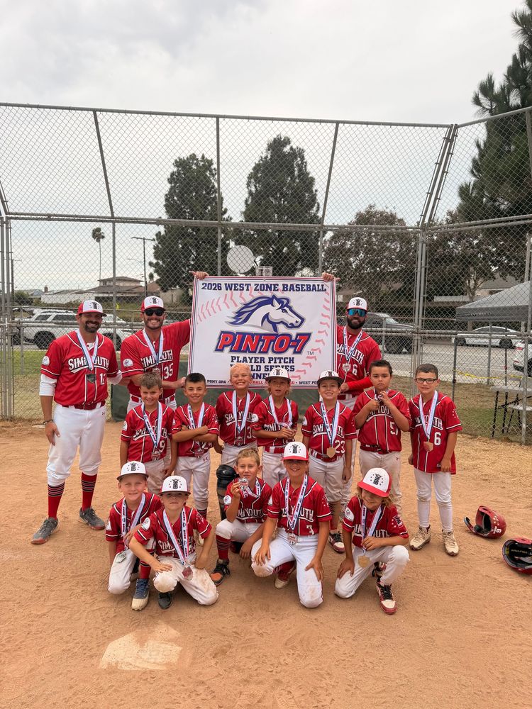 Youth baseball team posing on a field at night, holding a championship banner and trophy.