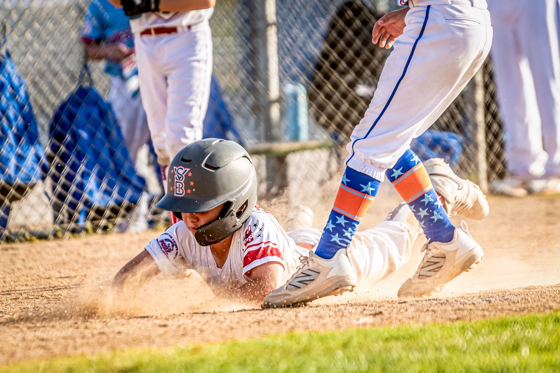 Baseball player sliding into home plate as a catcher tags him, kicking up dust