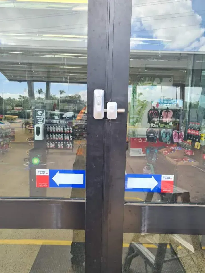 Glass Door with Locking Mechanism, Arrows Indicating Direction, Store Interior Visible Through the Glass — Nq Locksmiths In Kirwan, QLD