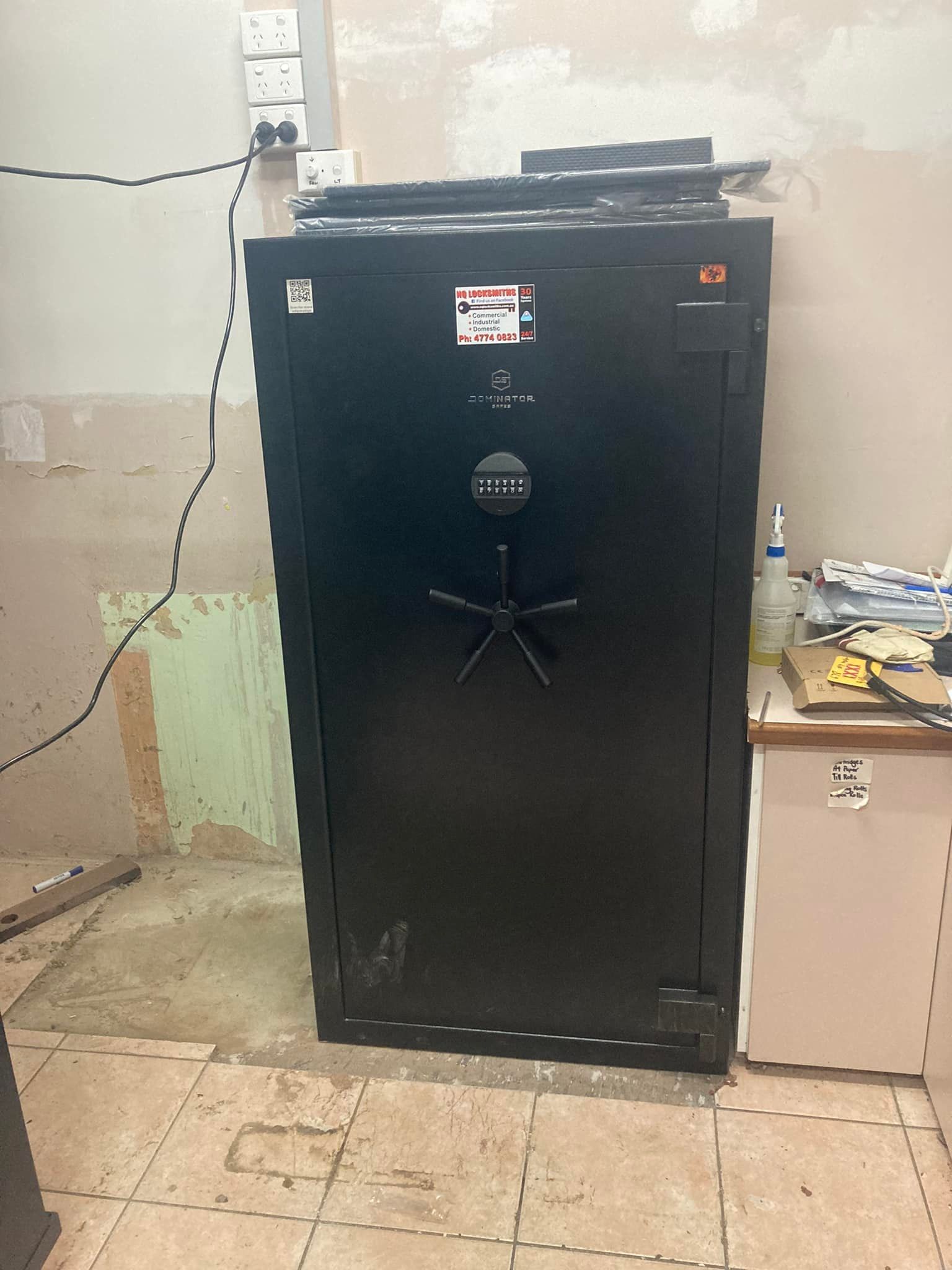 A Gray Safe with Open Door Sits in The Corner of A Room, with Electrical Cords and A Small Box on Top — Nq Locksmiths In Kirwan, QLD