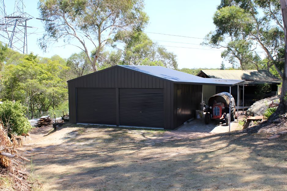 A Tractor is Parked in a Garage Next to a House — Mareeba Sheds & Gas In Mareeba, QLD