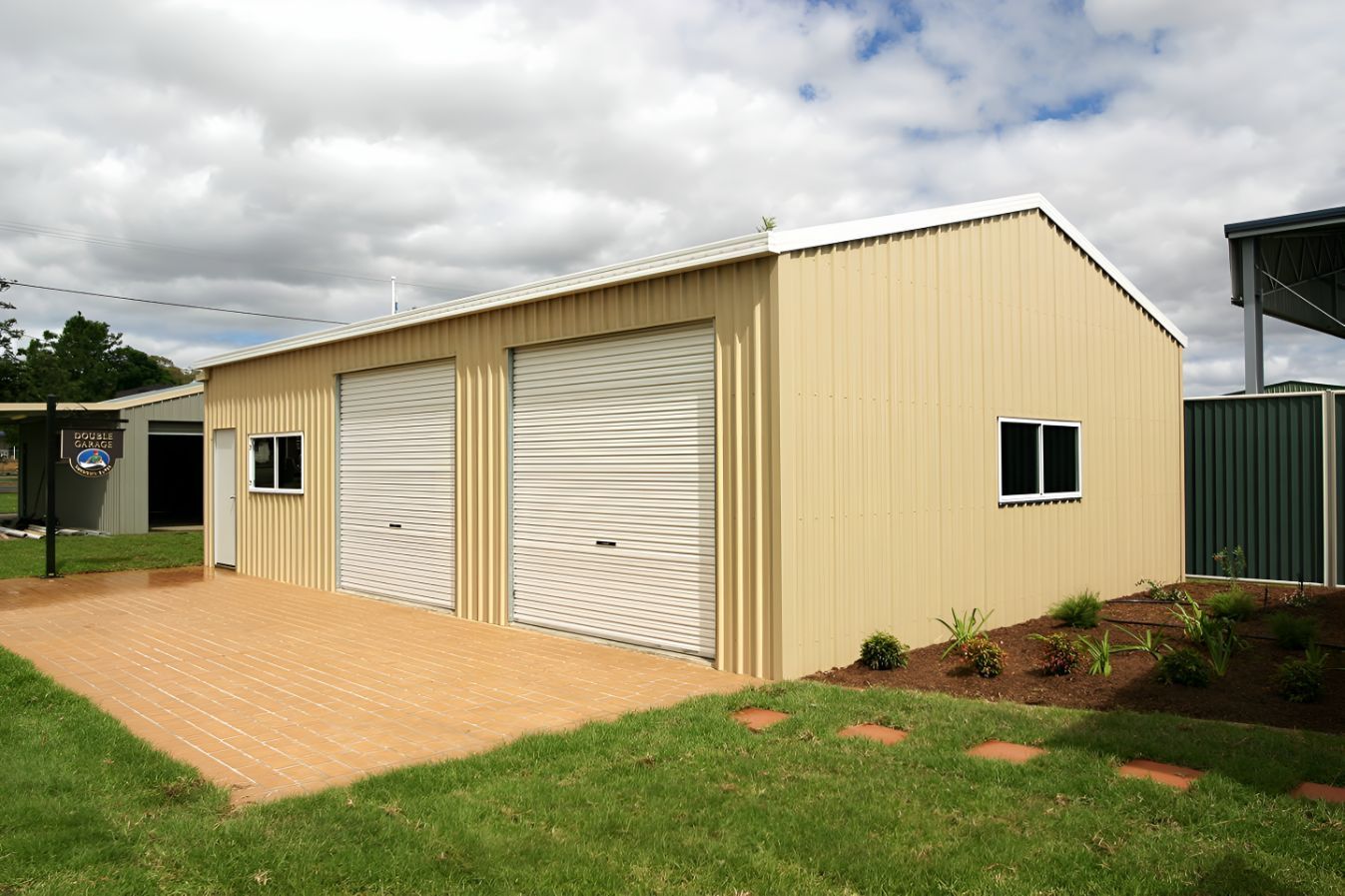 A Tan Garage With White Doors and Windows — Mareeba Sheds & Gas In Cairns, QLD