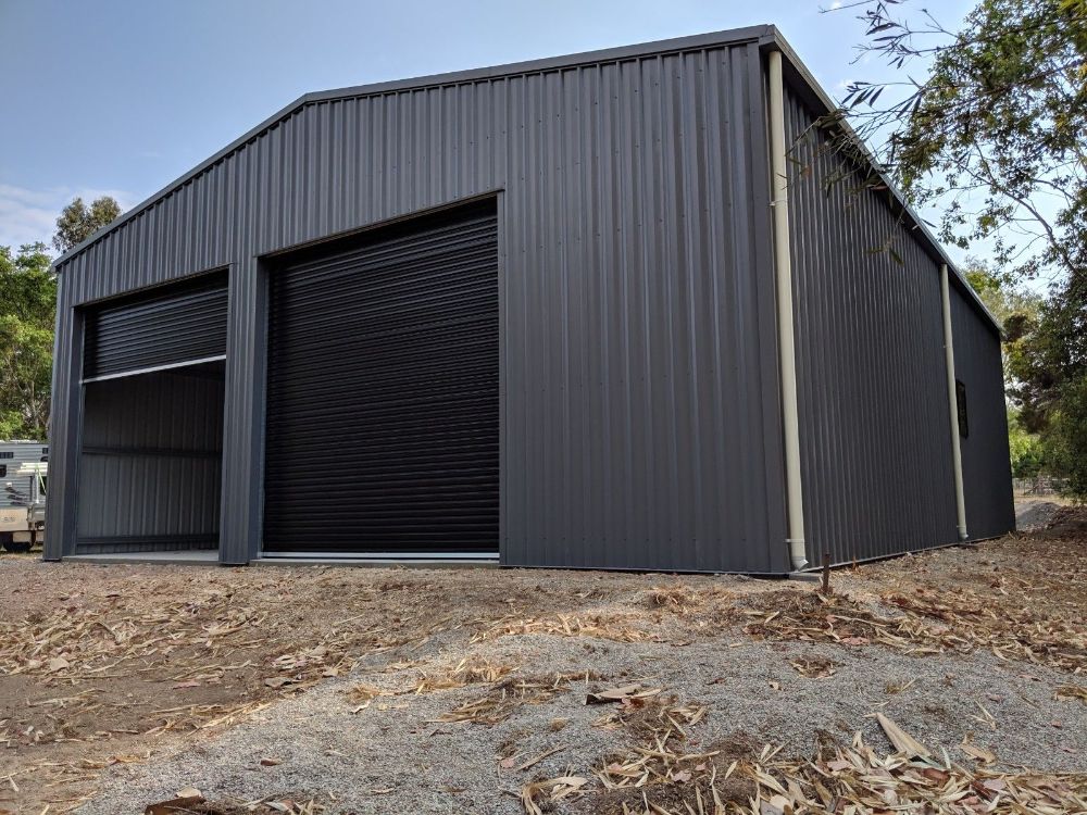 A Black Garage With a Driveway and Trees in the Background — Mareeba Sheds & Gas In Mareeba, QLD