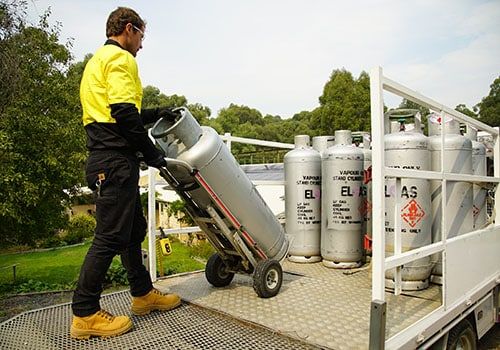 A Row of Blue Gas Cylinders Are Lined Up in a Warehouse — Mareeba Sheds & Gas In Mareeba, QLD