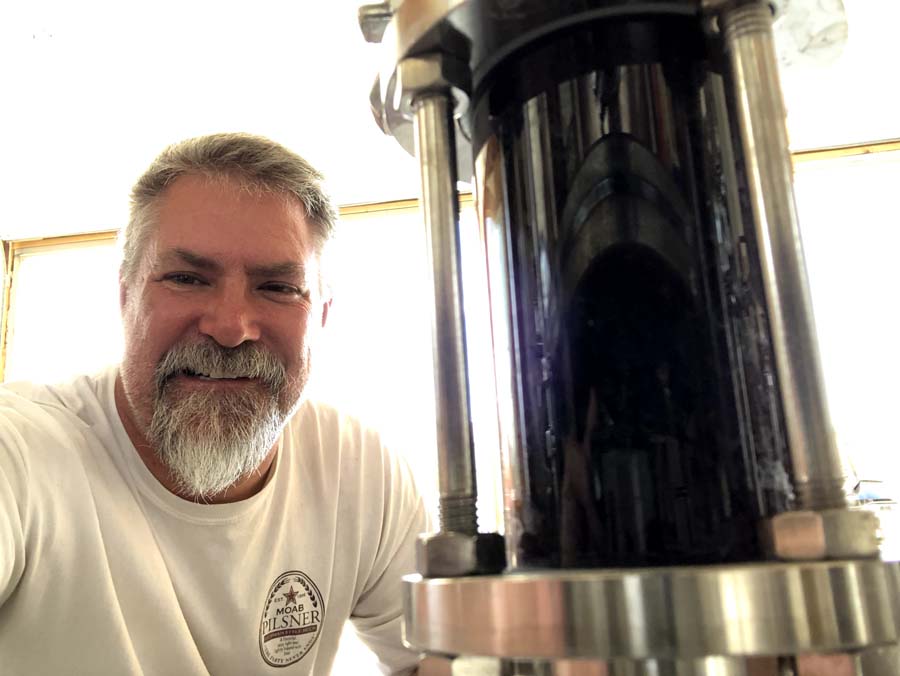A man with a beard is standing next to a machine