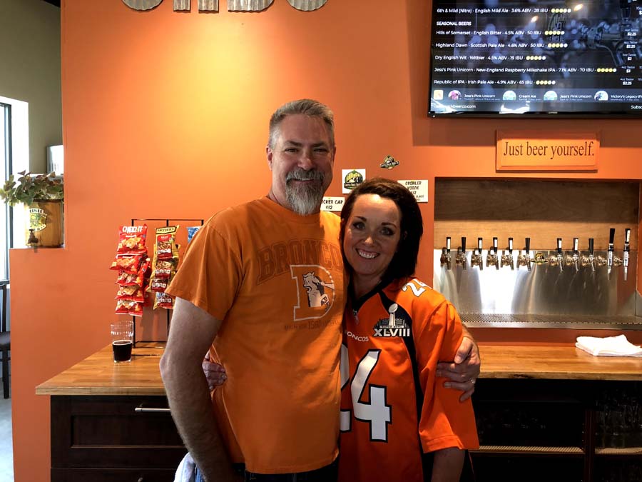 A man and a woman are posing for a picture and the woman is wearing a jersey with the number 14 on it