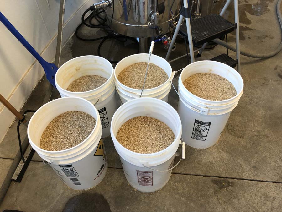 Several buckets filled with grain are sitting on the floor