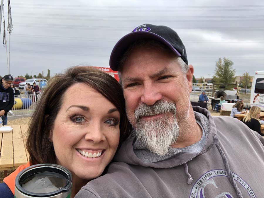 A man and a woman are posing for a picture and the woman is holding a cup.