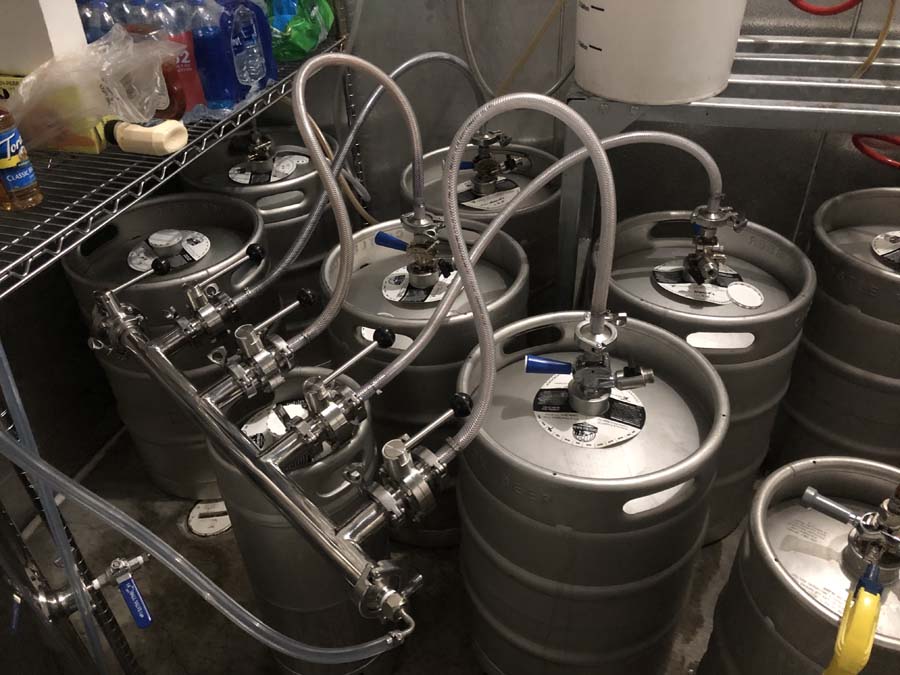 A bunch of kegs with hose attached to them