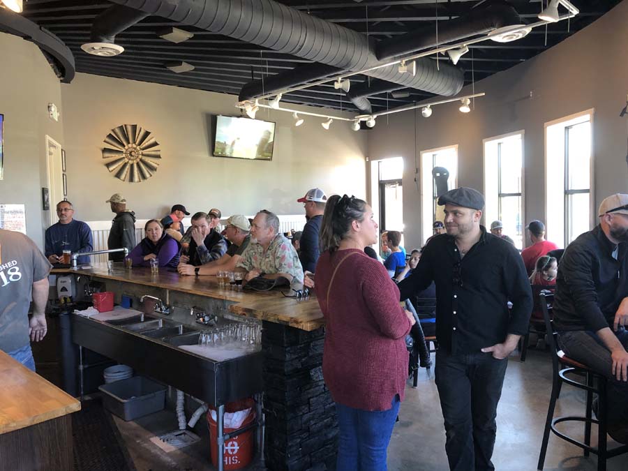 A group of people are standing around a bar in a restaurant.