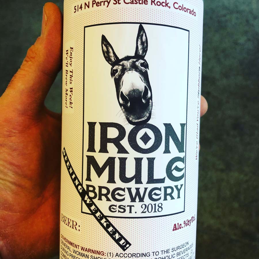 A person is holding a bottle of iron mule brewery