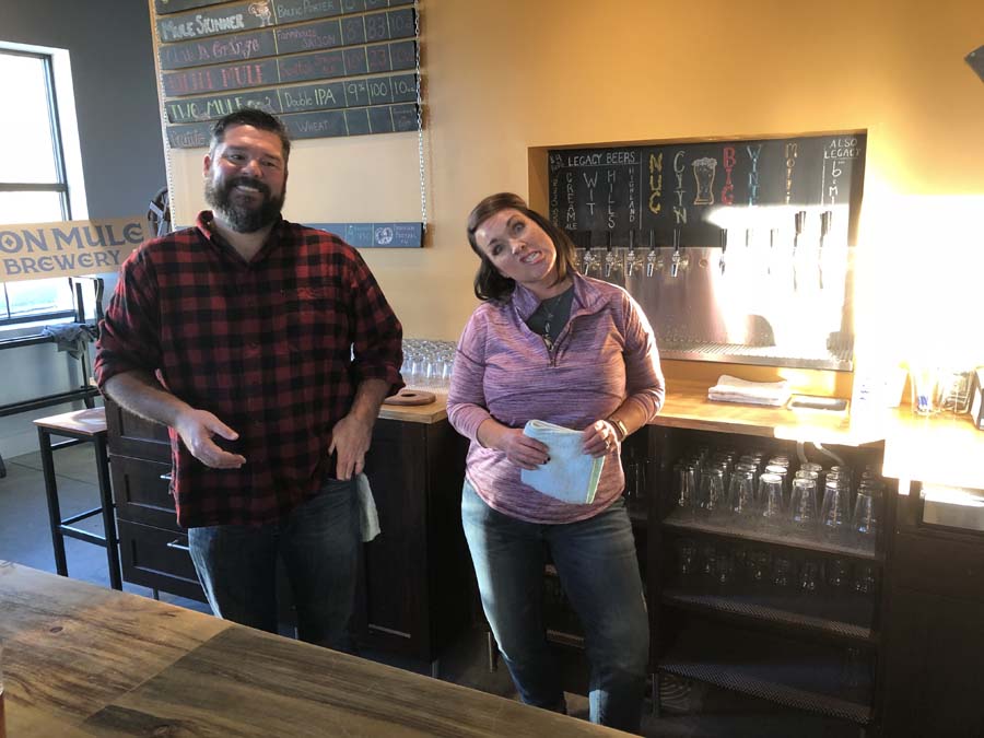 A man and a woman are standing next to each other in a restaurant.