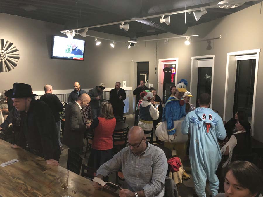 A group of people are standing around a bar in a restaurant.