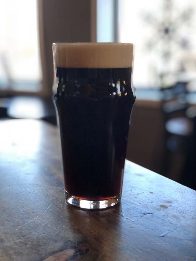 A glass of beer is sitting on a wooden table.