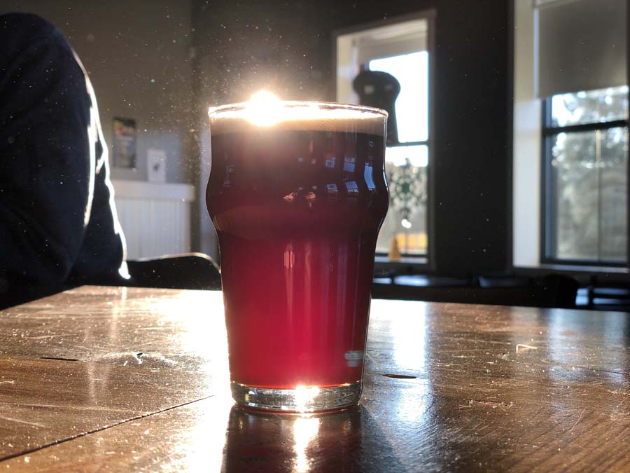 A glass of red liquid sits on a wooden table