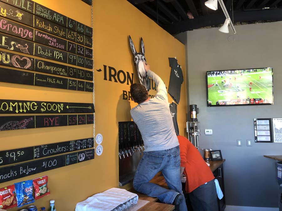A man is hanging a sign on a wall that says coming soon
