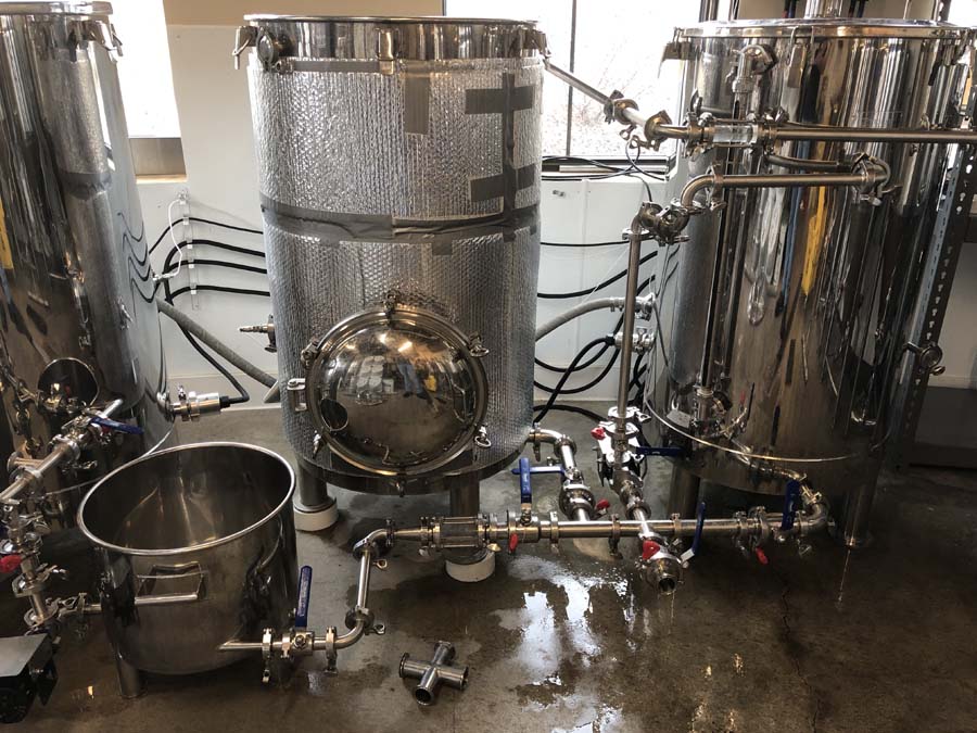 A bunch of stainless steel tanks are sitting on the floor