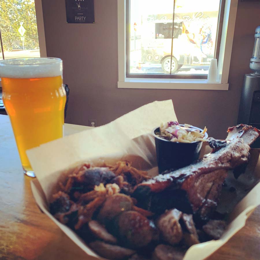 A bowl of food next to a glass of beer