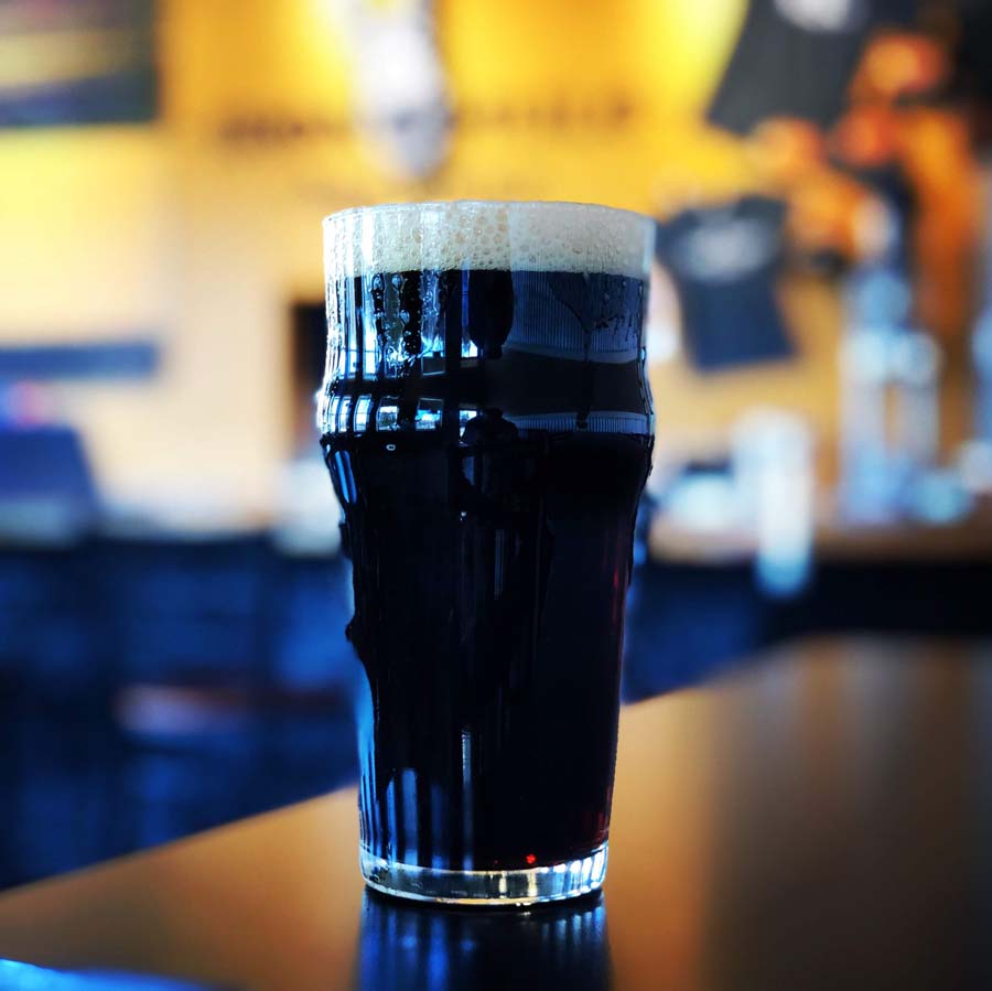 A glass of dark beer sits on a table