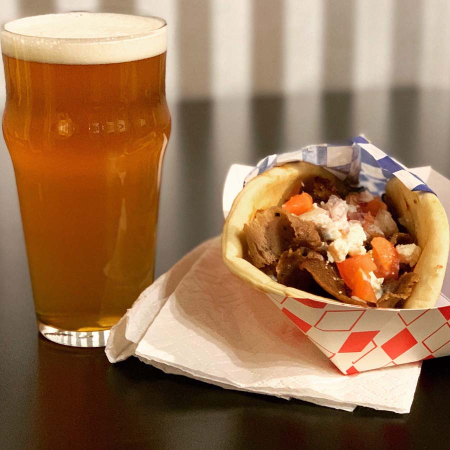 A gyro next to a glass of beer on a table