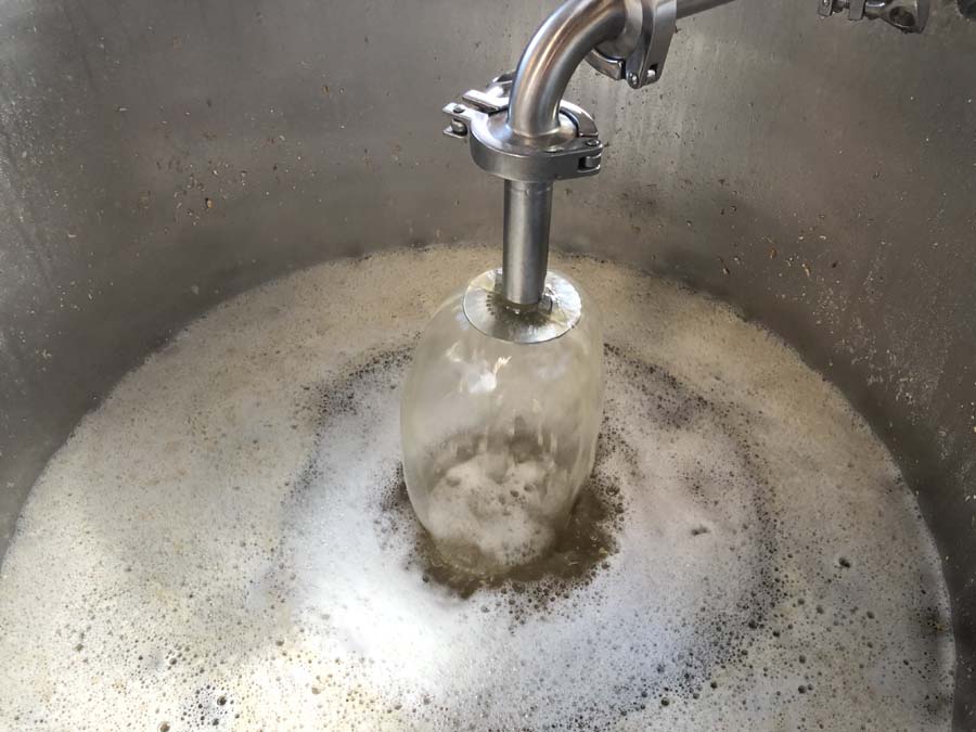 A jar is being stirred in a stainless steel pot filled with foam.