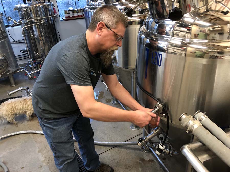 A man is working on a machine in a factory with a dog.