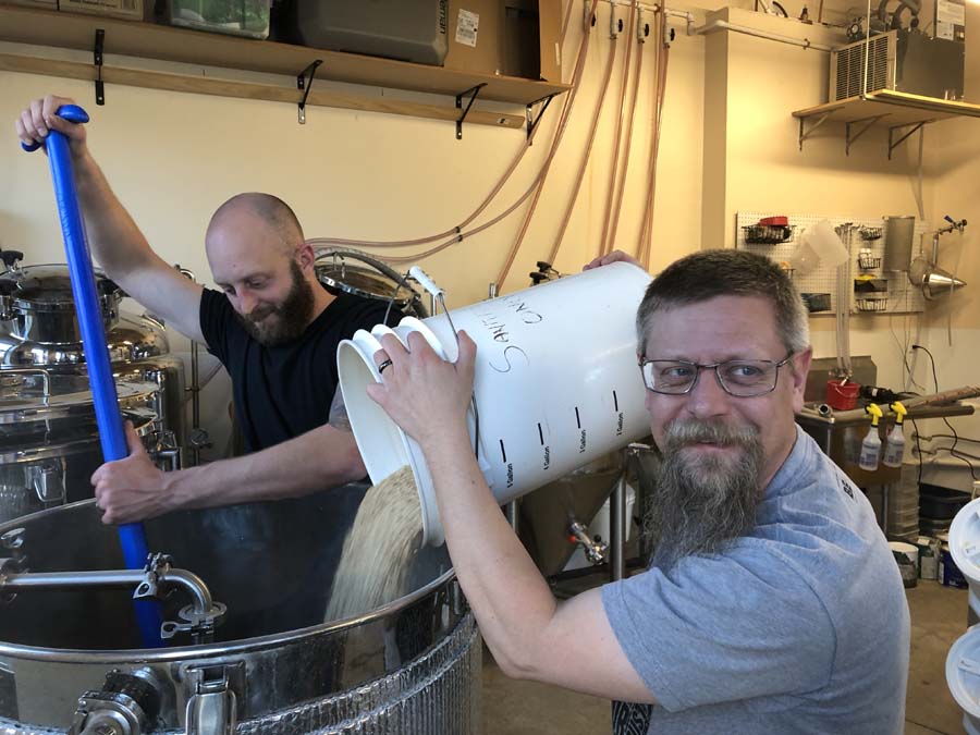 Two men are making beer in a brewery.