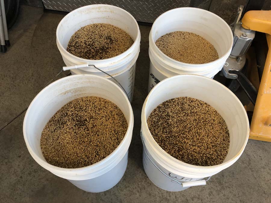 Four white buckets filled with different types of grains