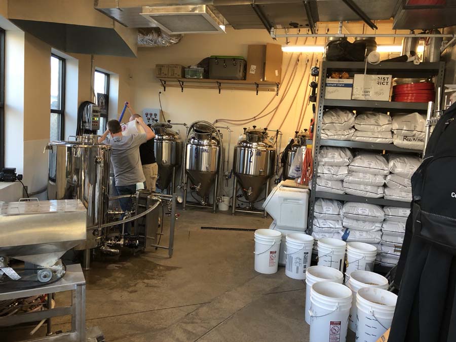 A man is working in a brewery surrounded by buckets and bags