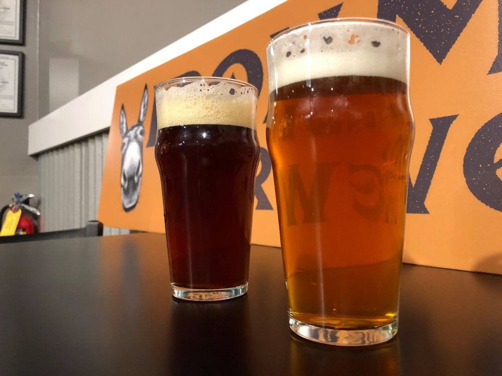 Two glasses of beer are on a table in front of a sign that says move