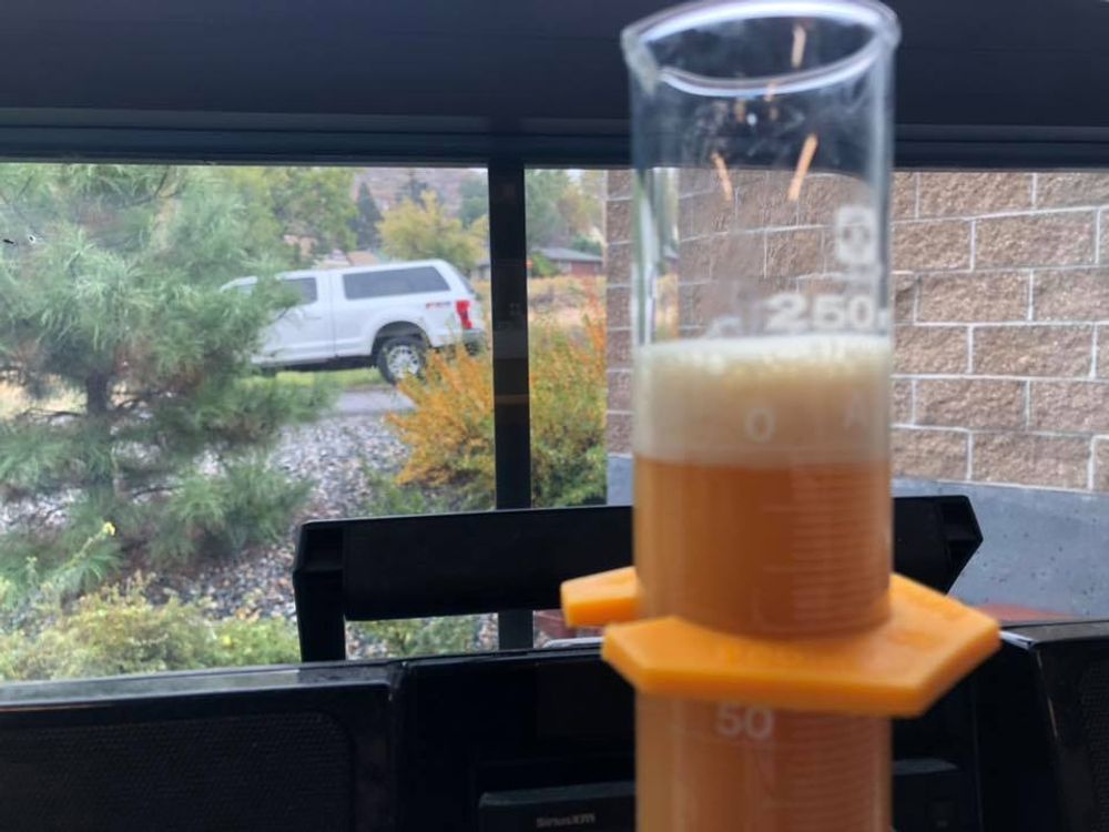 A beaker filled with liquid is sitting on a table in front of a window.
