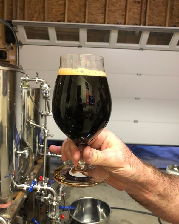 A person is holding a glass of beer in their hand