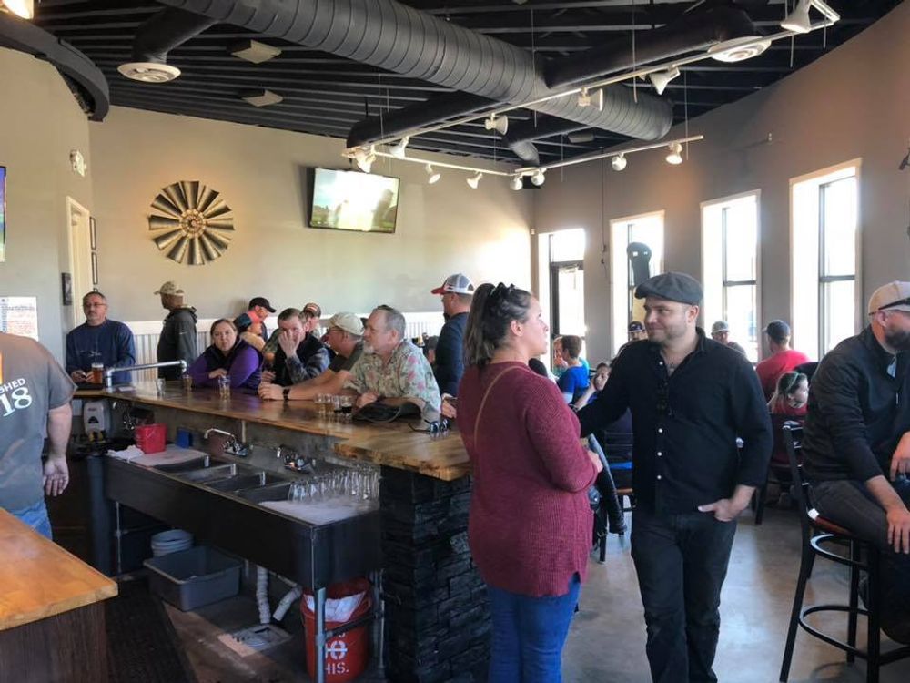 A group of people are standing around a bar in a restaurant.