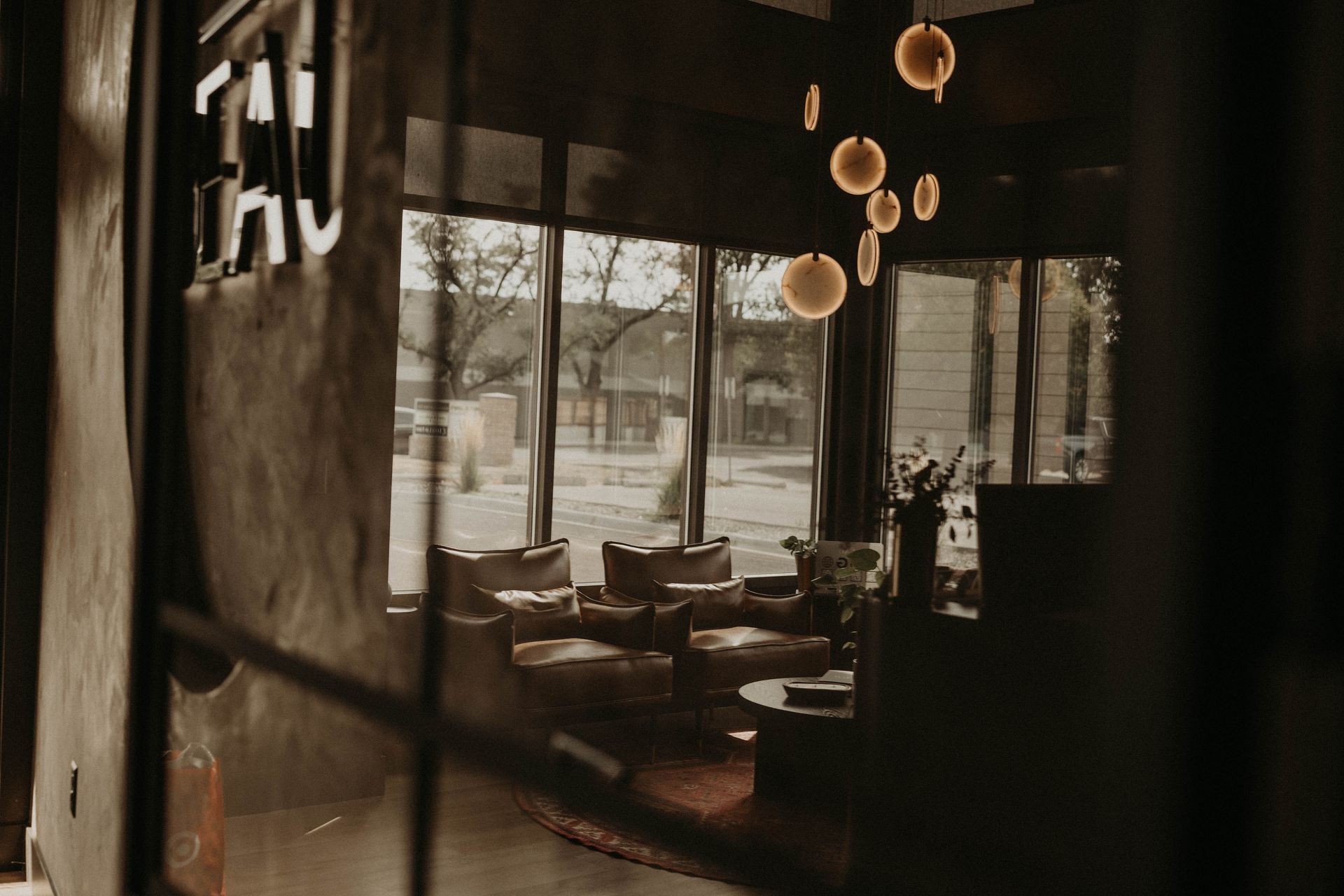 Interior shot of a modern lounge with sunlight, leather chairs, and a view of a street outside.