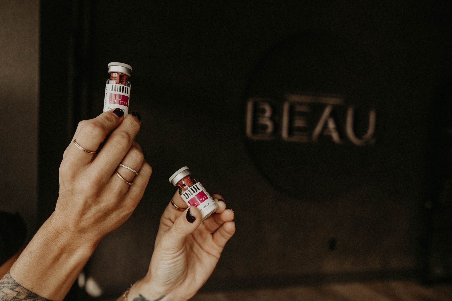 Hands holding two vials of liquid, in front of a dark wooden door with the word