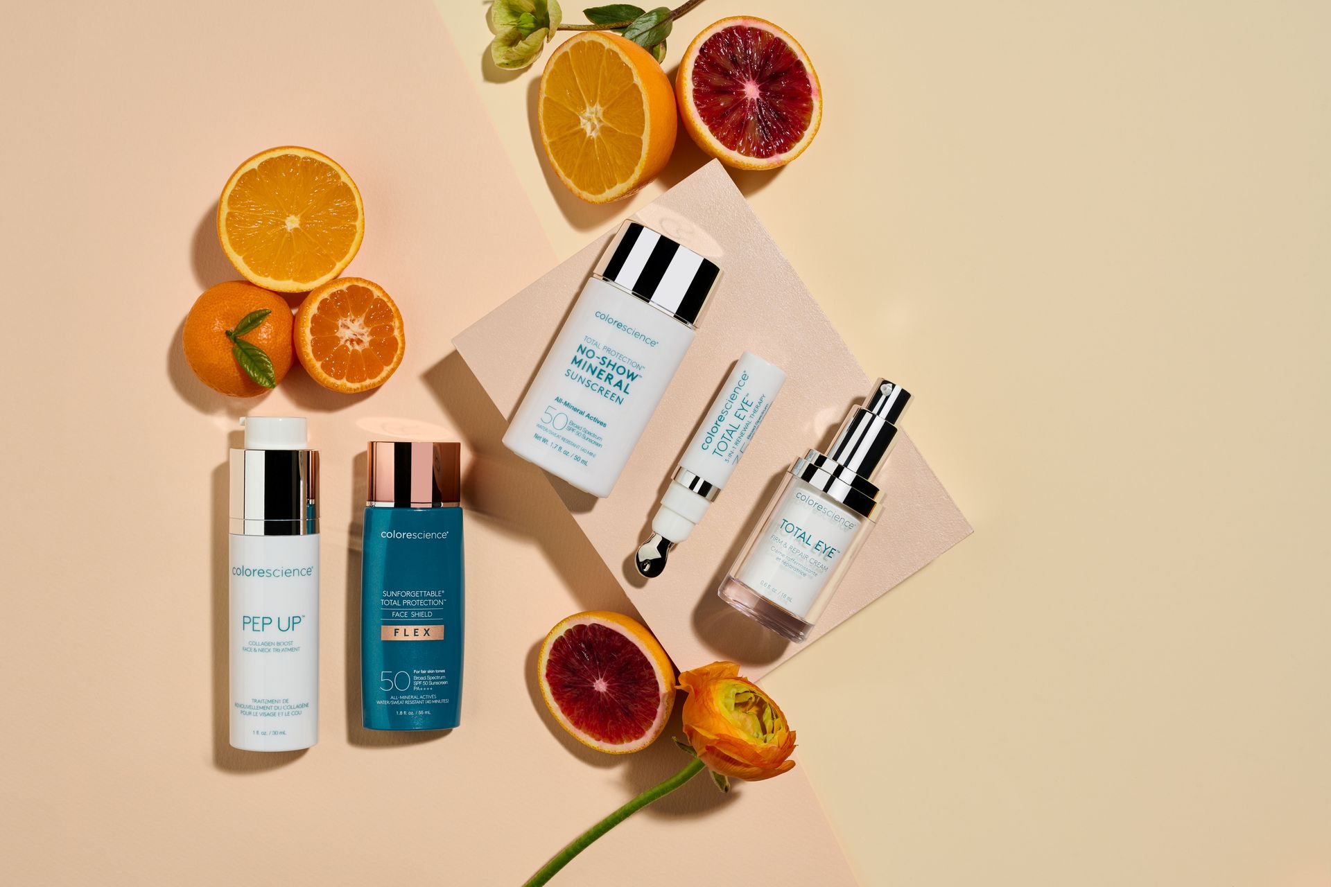 Skincare bottles with sliced citrus fruits arranged on a beige background