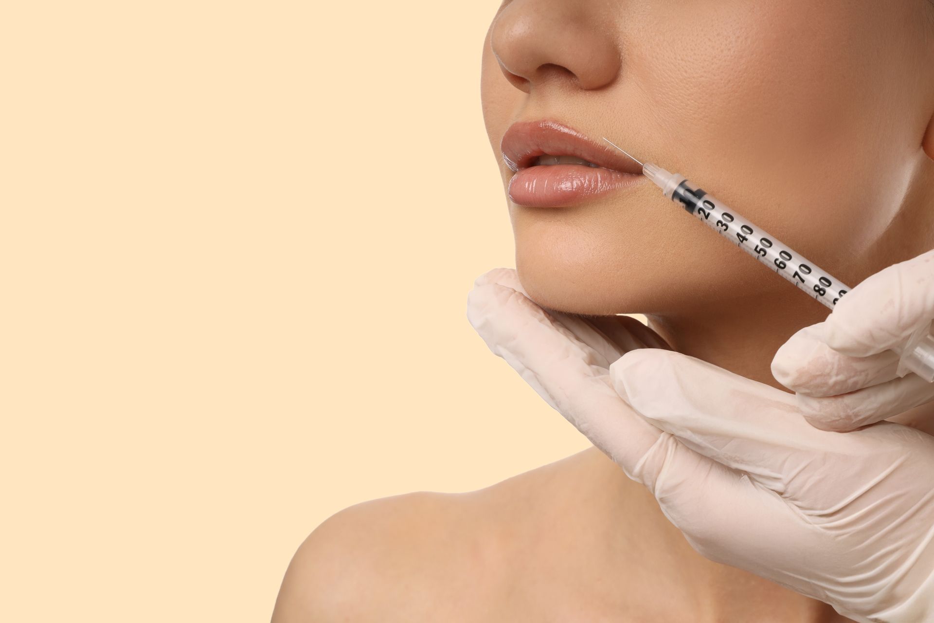Gloved hands inject filler into a woman’s lips against a beige background