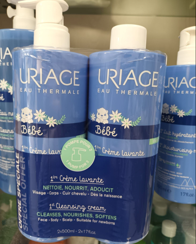 Flaconi di detergente per neonati Uriage Bébé di colore blu, con dosatore a pompa bianco ed etichette floreali, esposti su uno scaffale di un negozio.