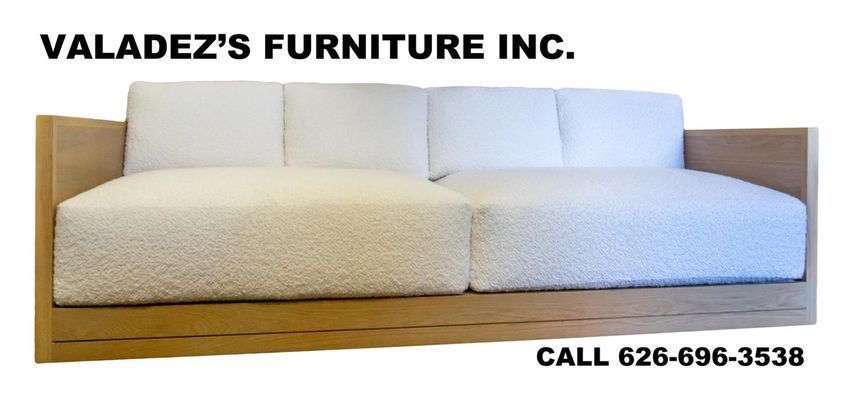 A cream-colored couch with white cushions and a wooden frame.
