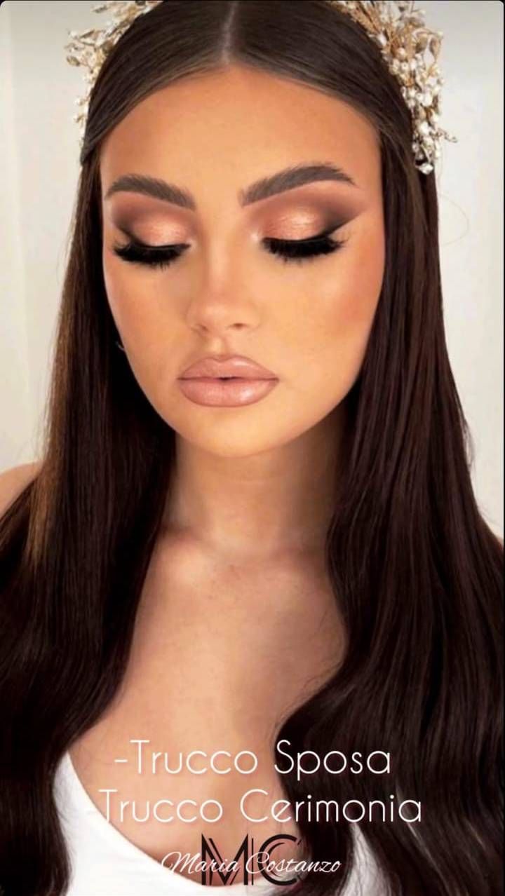 Donna con trucco glamour, ombretto marrone chiaro, ciglia folte e copricapo floreale.