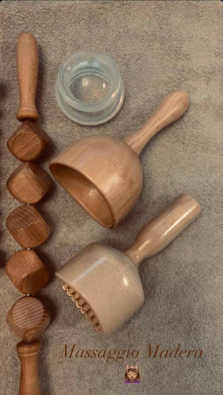 Strumenti in legno per massaggi terapeutici, tra cui strumenti a forma di cucchiaio e pomelli, disposti su un asciugamano.