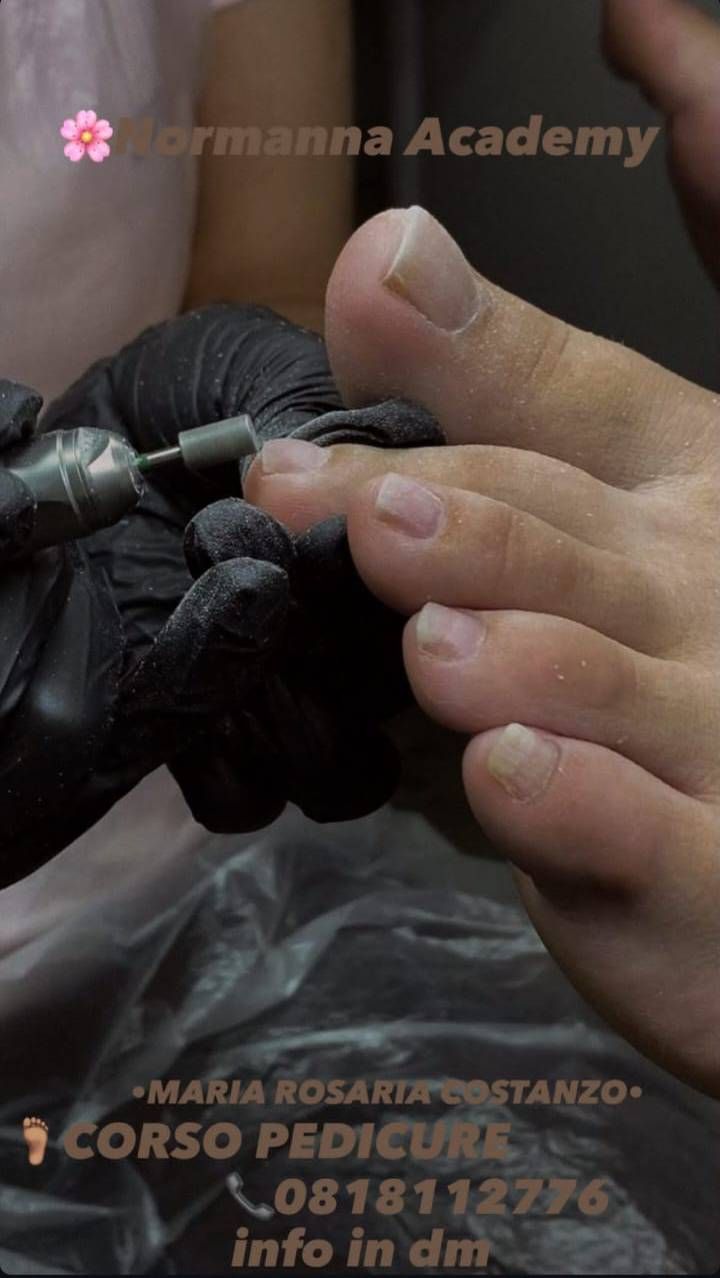 Persona che riceve una pedicure. Mano guantata di un'estetista che usa uno strumento su un piede.