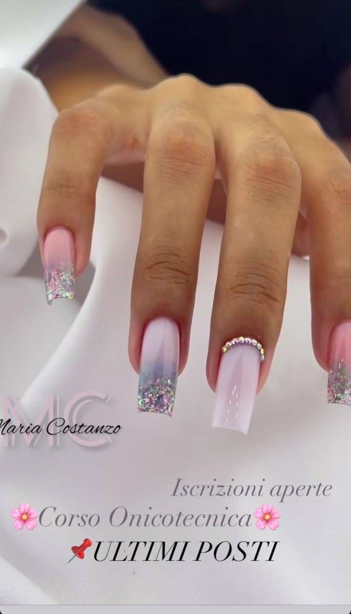 Mano con unghie quadrate; design sfumato rosa chiaro con glitter argento e strass.