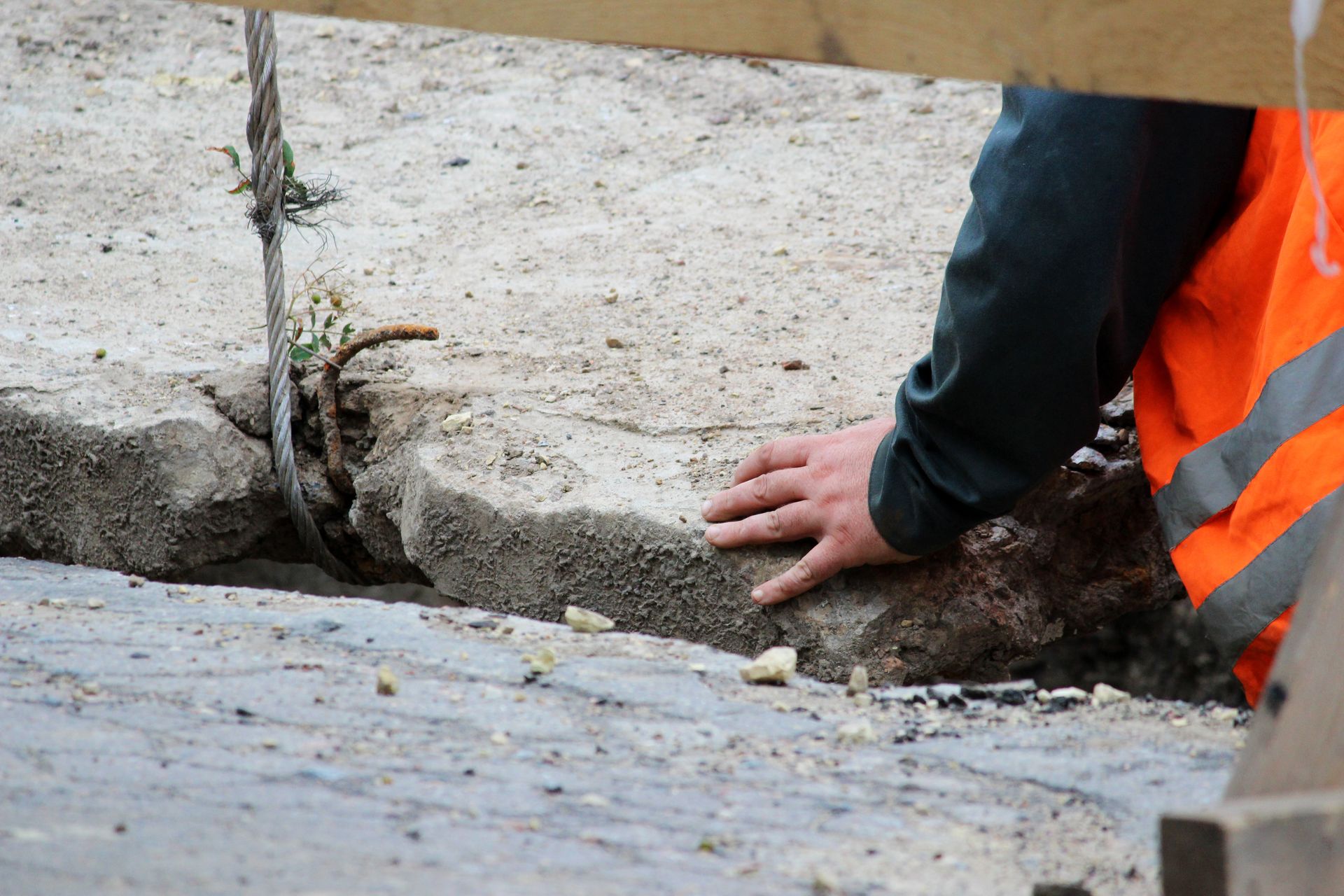 Slab Leak Crack - Worker in orange safety vest inspecting a cracked concrete curb and drainage ditch - Savannah, GA