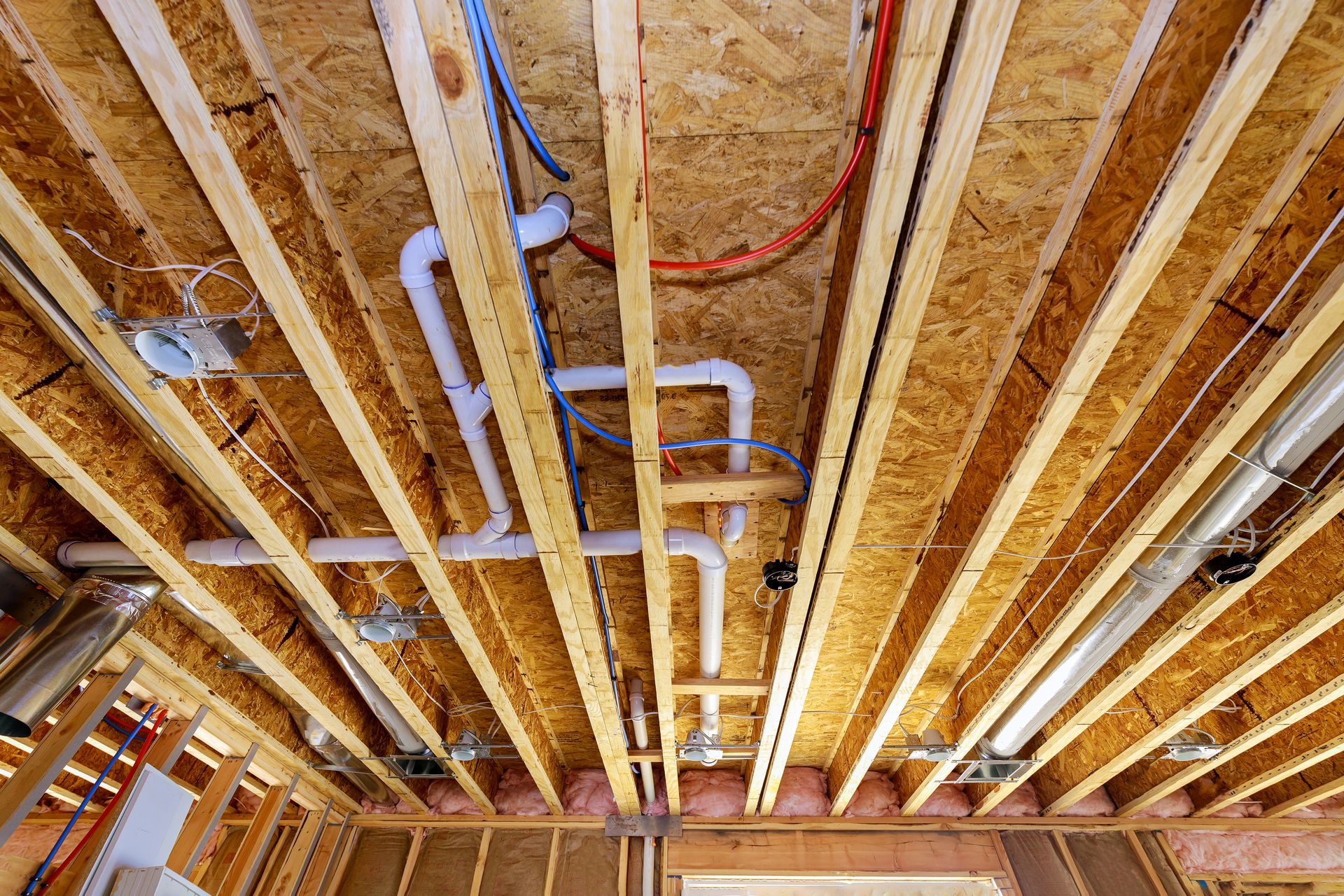 Plumbing Remodeling - Exposed basement ceiling framing with pipes, ducts, and electrical wiring during construction - Savannah, GA