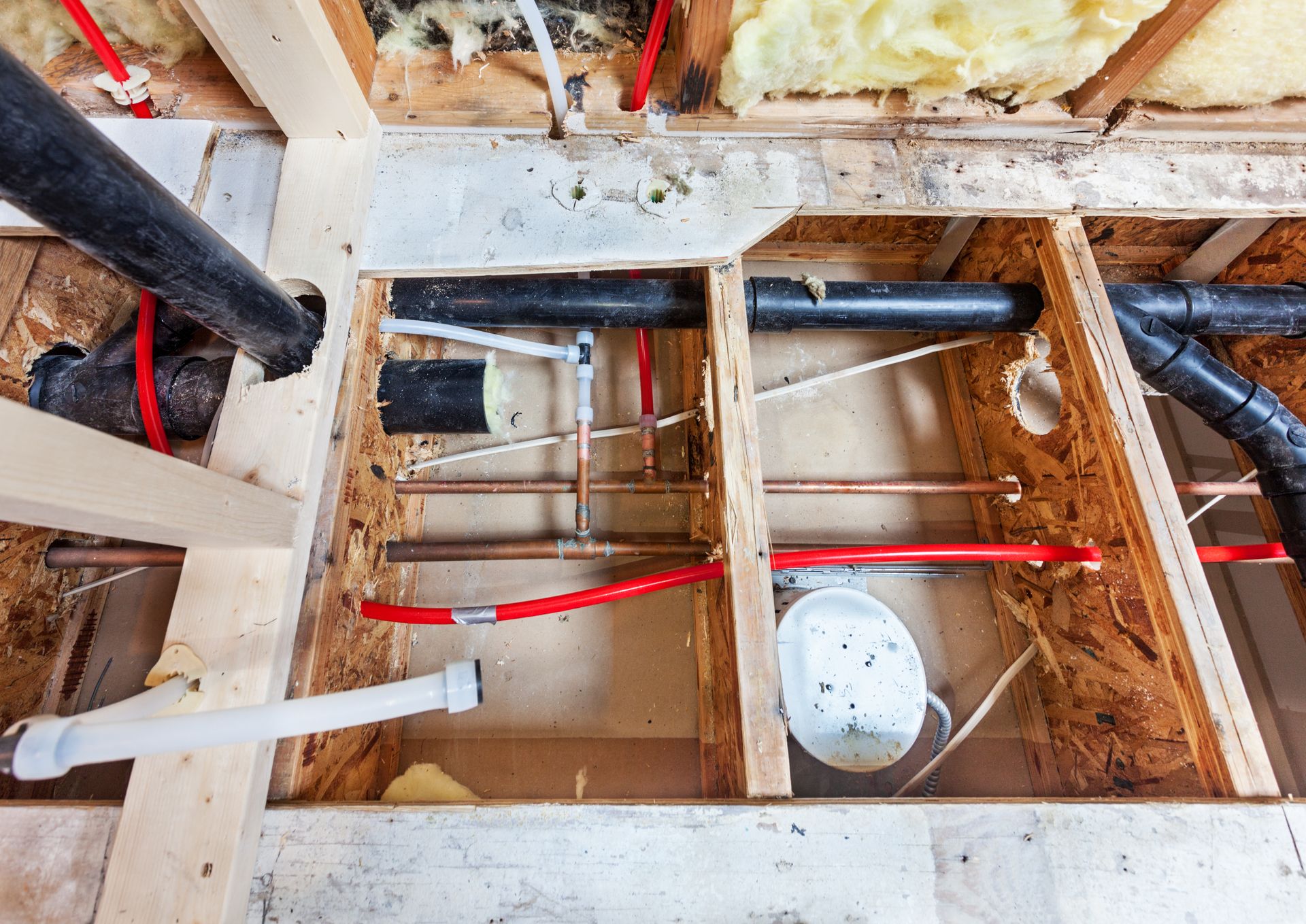 Slab Leak Repair - Exposed floor joists with plumbing and wiring in a construction renovation area - Savannah, GA