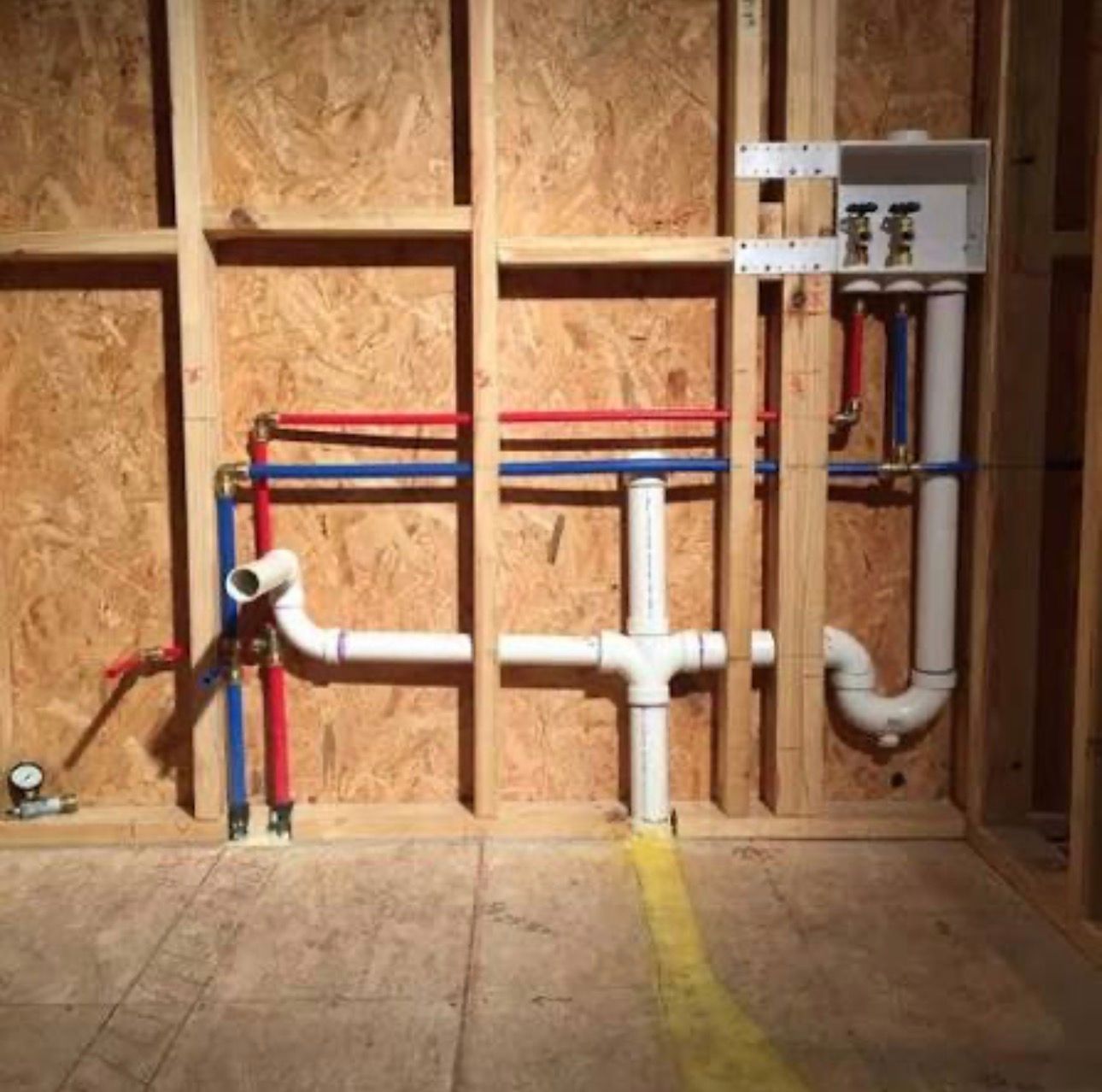 Exposed basement ceiling framing with pipes, ducts, and electrical wiring during construction